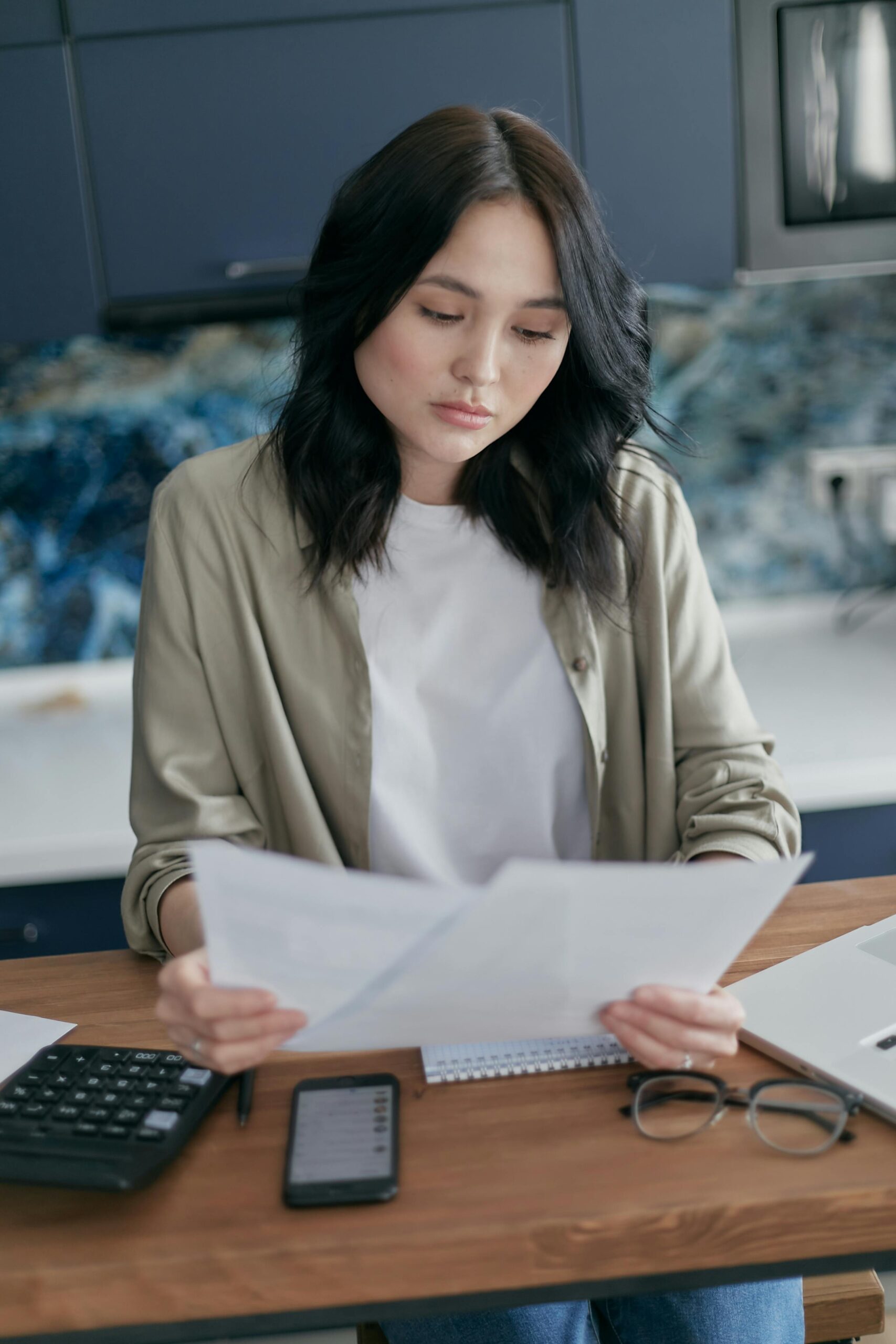 Woman reviewing personal finances and budgeting plan with phone and notebook