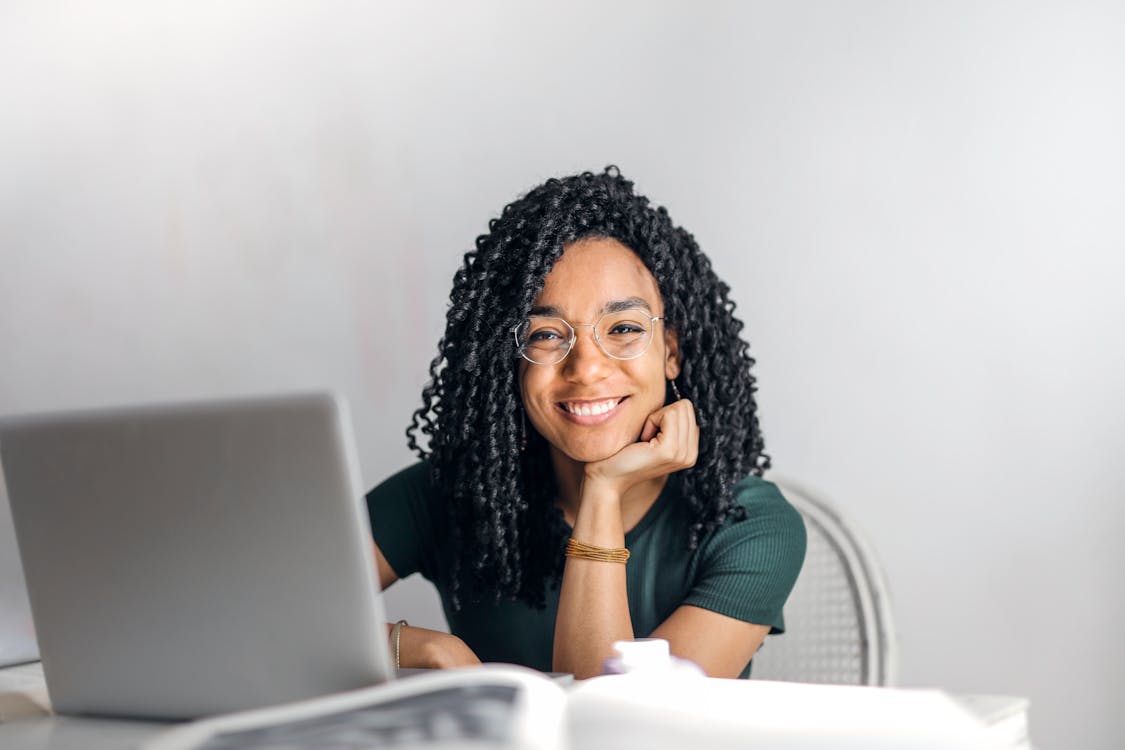 Smiling woman sitting at laptop feeling confident and in control of her personal finances